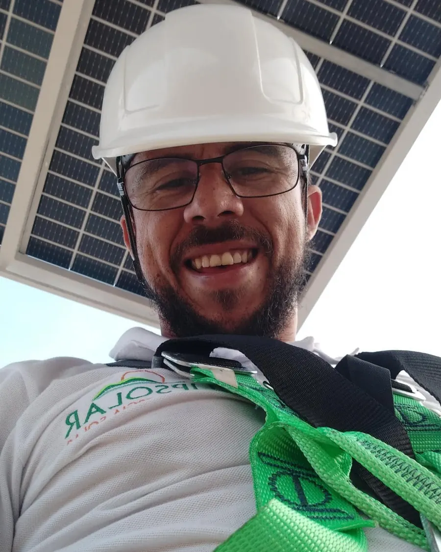 Técnico da LipSolar com capacete e cinto de segurança embaixo de painel solar instalado