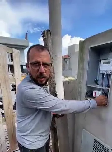 Felipe, fundador da LipSolar, instalando disjuntor e DPS em quadro elétrico externo