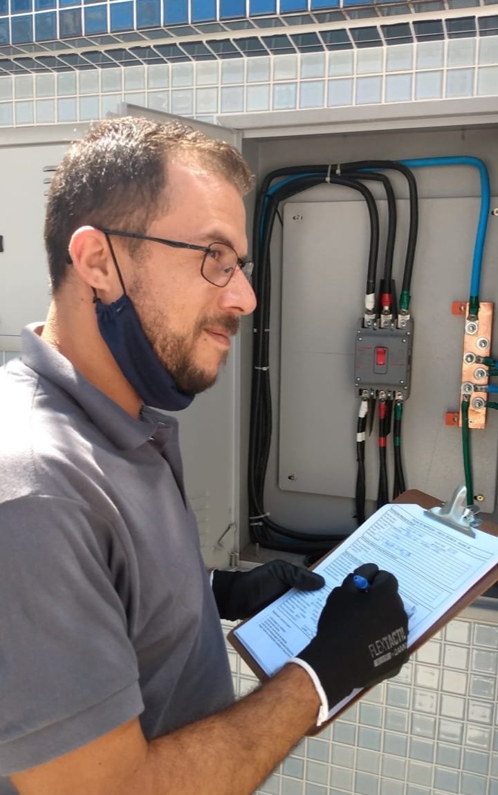 Felipe, fundador e CEO da LipSolar Solutions, realizando vistoria técnica em quadro elétrico com prancheta