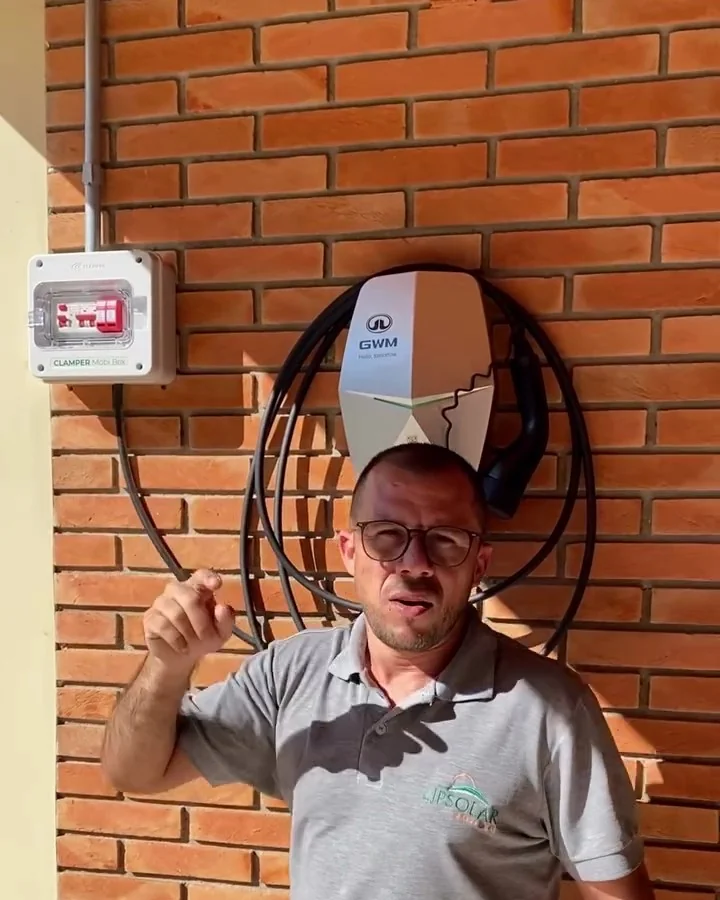 Felipe, técnico da LipSolar, ao lado de wallbox GWM instalado em parede de tijolo aparente